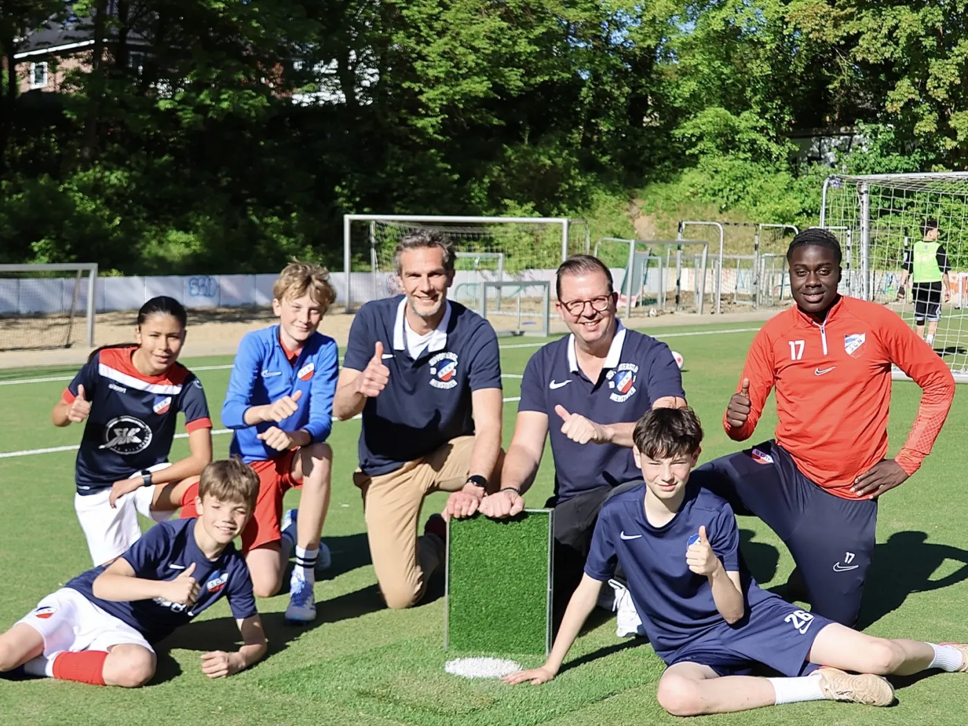 Vorstand und Kinder des SC Nienstedten mit einem Muster des neuen Zukunftsrasens auf dem Platz am Quellental